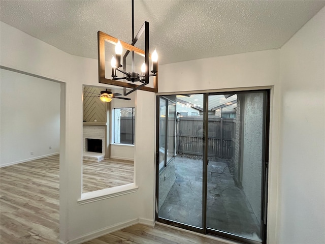 doorway to outside featuring ceiling fan with notable chandelier, hardwood / wood-style floors, and a textured ceiling