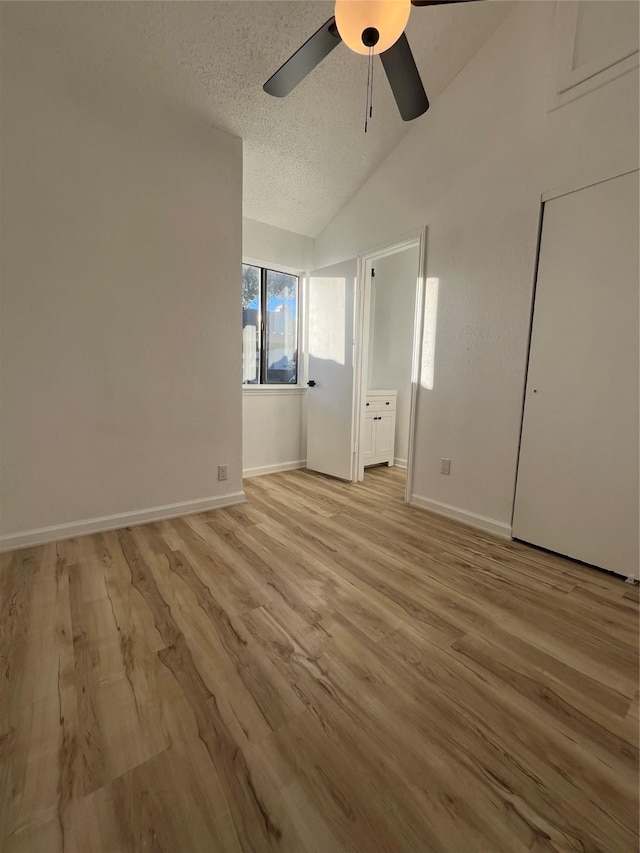 unfurnished bedroom with lofted ceiling, light wood-type flooring, a textured ceiling, and ceiling fan