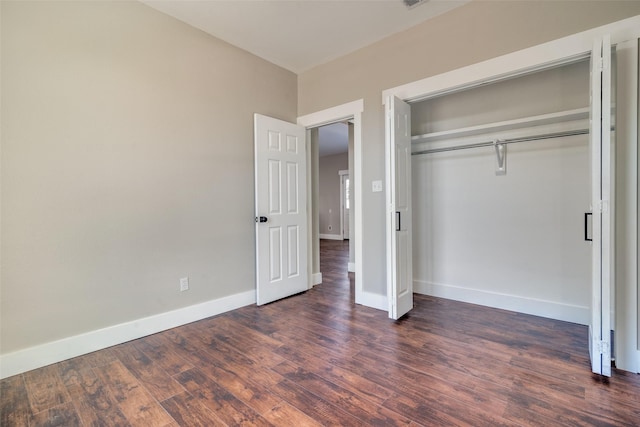 unfurnished bedroom with dark hardwood / wood-style flooring and a closet