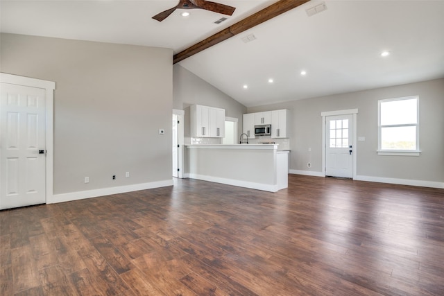 unfurnished living room with dark wood-type flooring, high vaulted ceiling, sink, ceiling fan, and beam ceiling