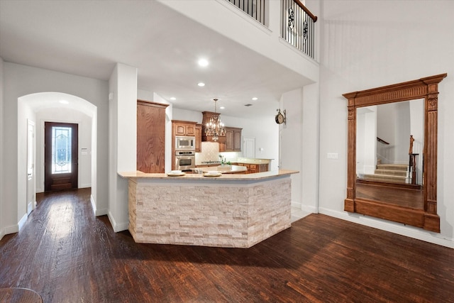 kitchen with kitchen peninsula, pendant lighting, a chandelier, dark hardwood / wood-style floors, and appliances with stainless steel finishes