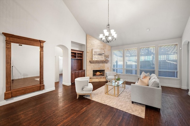 living room with a chandelier, dark wood-type flooring, high vaulted ceiling, a fireplace, and built in shelves