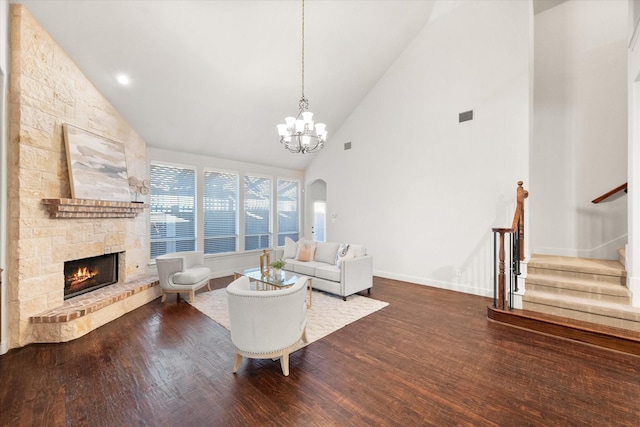 living room with a fireplace, high vaulted ceiling, hardwood / wood-style flooring, and an inviting chandelier