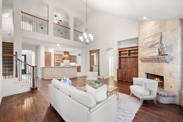 living room with a fireplace, high vaulted ceiling, built in shelves, and hardwood / wood-style flooring