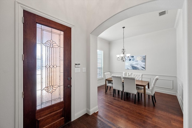 entrance foyer featuring dark hardwood / wood-style flooring, a chandelier, and ornamental molding