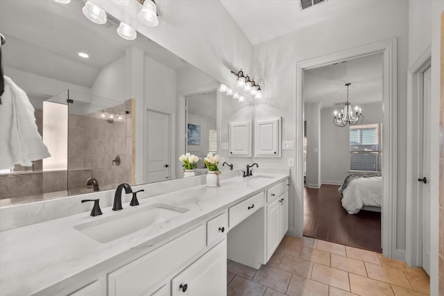 bathroom featuring vanity, tile patterned flooring, a notable chandelier, and tiled shower