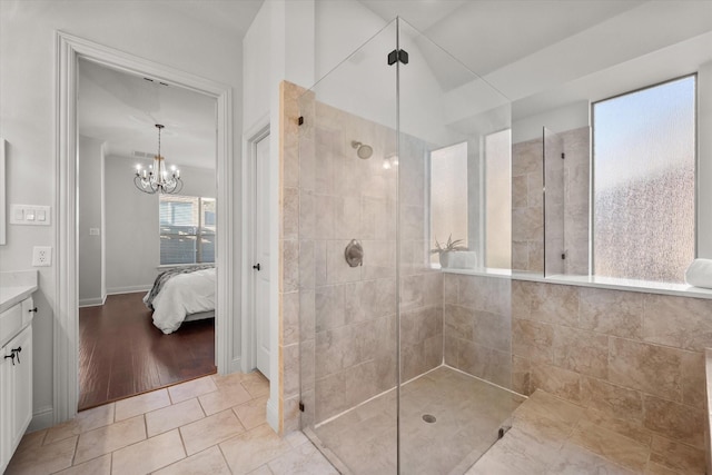 bathroom with a chandelier, tile patterned floors, a tile shower, and vanity