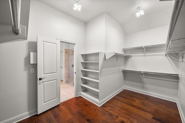 spacious closet with lofted ceiling and dark wood-type flooring