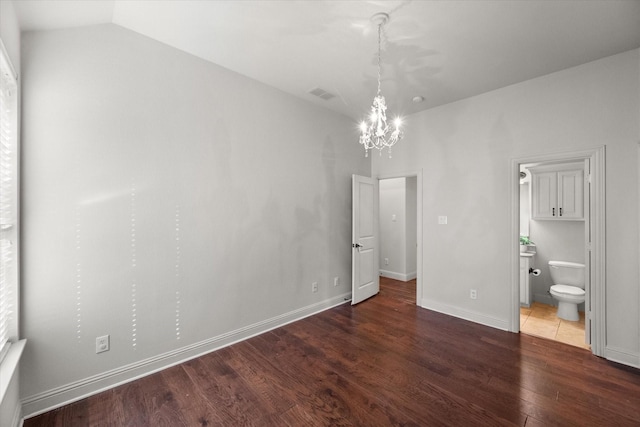 unfurnished bedroom featuring an inviting chandelier, vaulted ceiling, and dark wood-type flooring