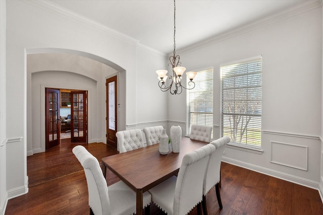 dining space featuring dark wood-type flooring, french doors, an inviting chandelier, and crown molding