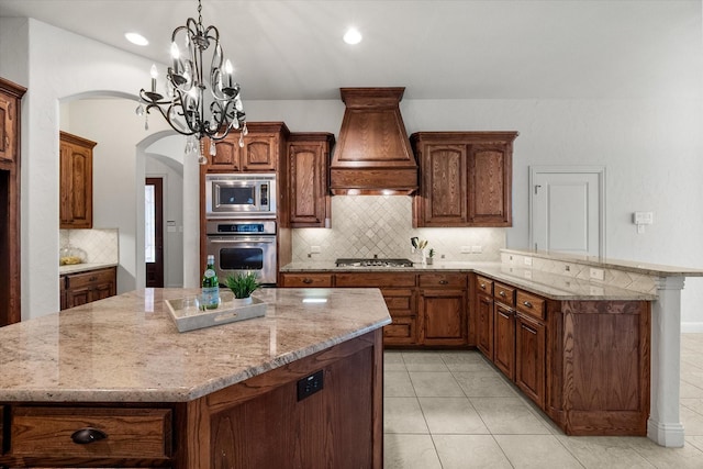 kitchen with stainless steel appliances, custom range hood, and a center island