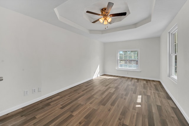 spare room with ceiling fan, dark wood-type flooring, and a tray ceiling