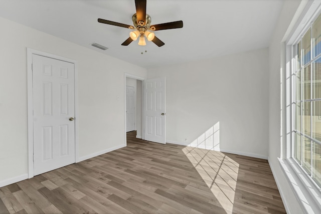 spare room featuring ceiling fan, a healthy amount of sunlight, and hardwood / wood-style flooring