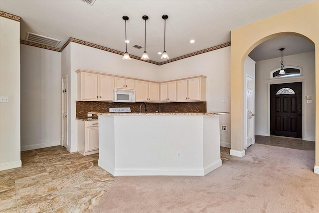 kitchen featuring arched walkways, white microwave, cream cabinets, and visible vents