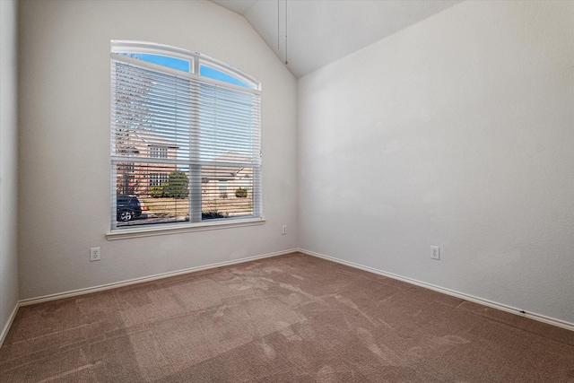 carpeted spare room featuring lofted ceiling, a wealth of natural light, and baseboards