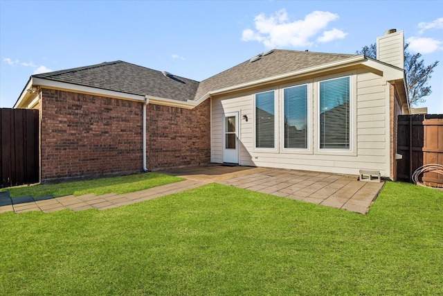 back of house featuring a yard, a shingled roof, fence, and brick siding