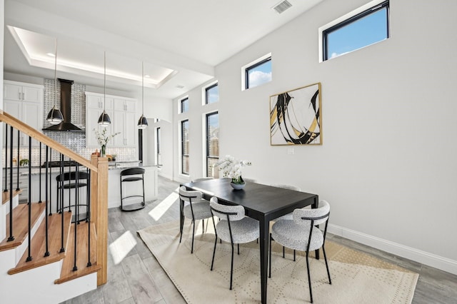 dining room with a raised ceiling and light hardwood / wood-style floors