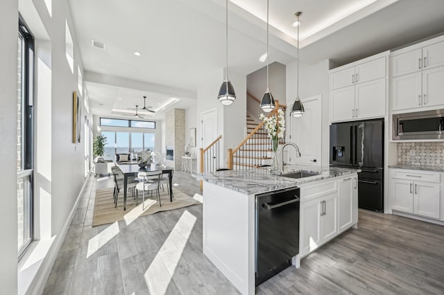 kitchen featuring black appliances, sink, a tray ceiling, decorative light fixtures, and white cabinetry