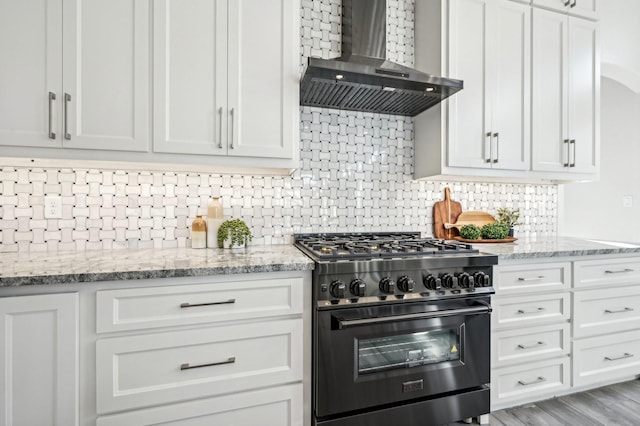 kitchen with wall chimney exhaust hood, high end black range oven, and white cabinetry