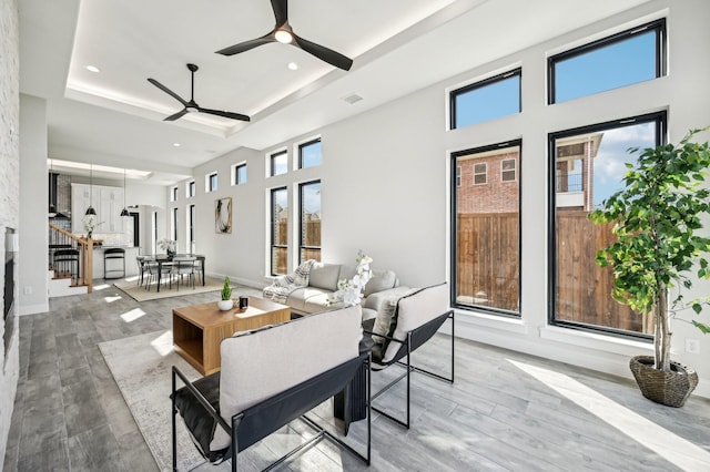 living room with ceiling fan and a raised ceiling