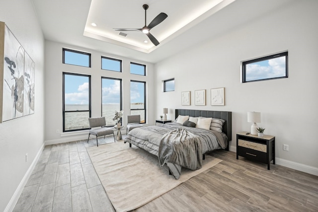 bedroom with a raised ceiling, ceiling fan, and hardwood / wood-style flooring