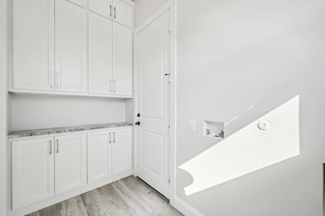 clothes washing area with cabinets, hookup for a washing machine, and light hardwood / wood-style flooring