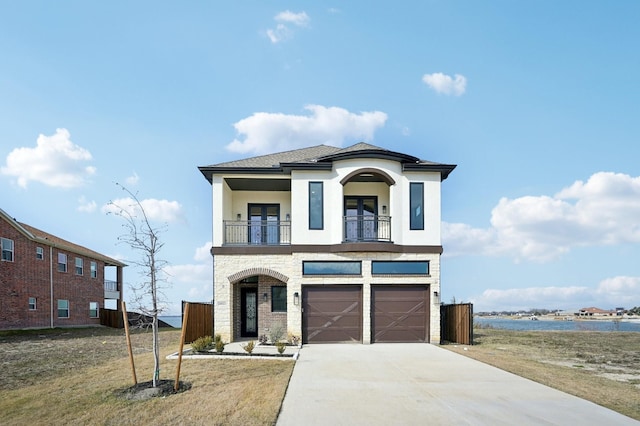 view of front of house with a balcony, a water view, a front yard, and a garage