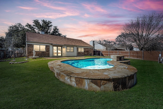 pool at dusk featuring a lawn