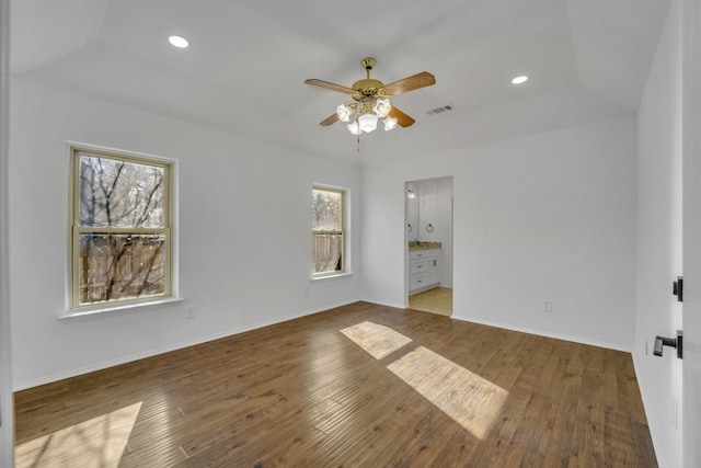 unfurnished bedroom featuring multiple windows, hardwood / wood-style floors, ceiling fan, and ensuite bath