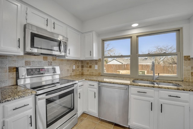 kitchen with stainless steel appliances, light stone countertops, sink, and white cabinets