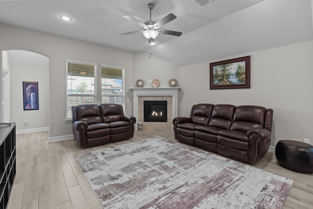 living room with ceiling fan, light hardwood / wood-style floors, lofted ceiling, and a fireplace