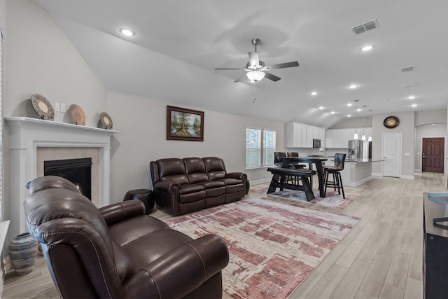 living room with ceiling fan, light hardwood / wood-style floors, and lofted ceiling