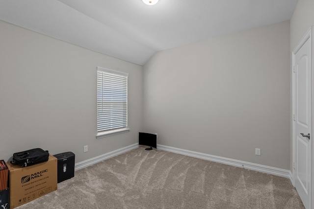 carpeted spare room featuring vaulted ceiling