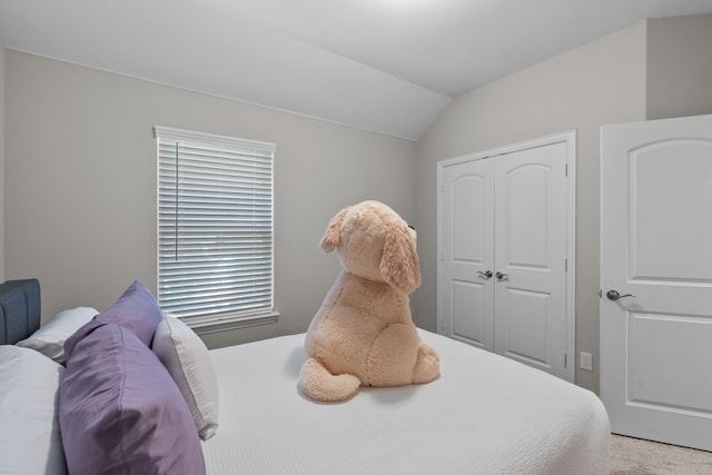 bedroom with light colored carpet, a closet, and lofted ceiling