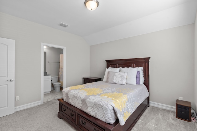 bedroom featuring ensuite bath, light colored carpet, and lofted ceiling