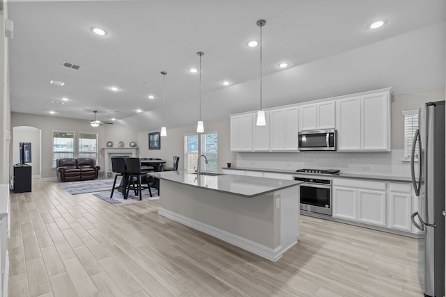 kitchen featuring white cabinets, sink, stainless steel appliances, and hanging light fixtures