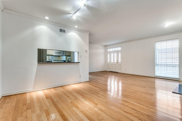 unfurnished living room with light hardwood / wood-style floors, ornamental molding, and track lighting