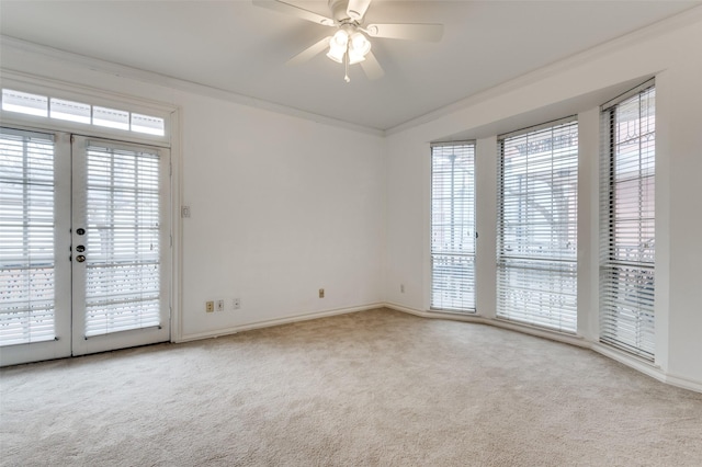 empty room featuring light carpet, french doors, ceiling fan, and ornamental molding