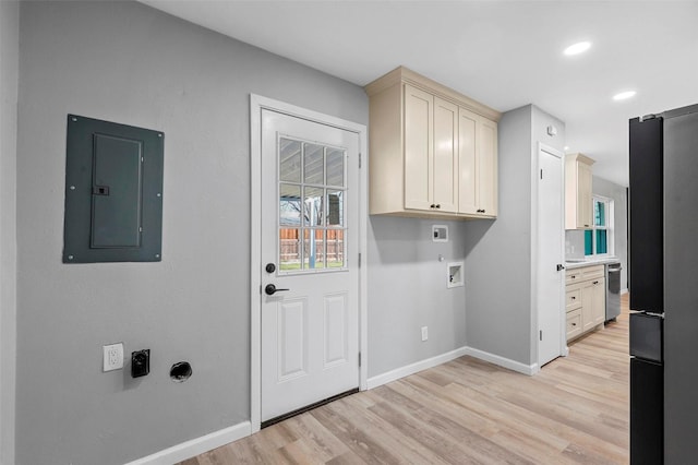 laundry room featuring electric panel, hookup for a washing machine, light hardwood / wood-style flooring, electric dryer hookup, and cabinets