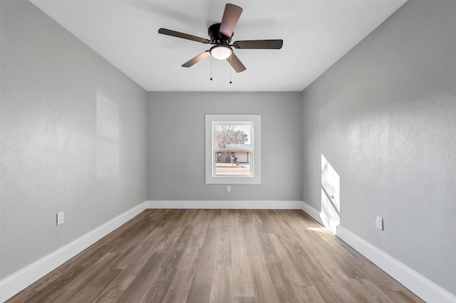 empty room featuring a ceiling fan, baseboards, and wood finished floors