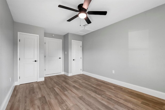 unfurnished bedroom with a ceiling fan, visible vents, baseboards, and wood finished floors