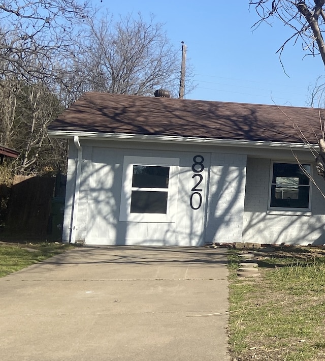 view of front of house featuring roof with shingles and brick siding