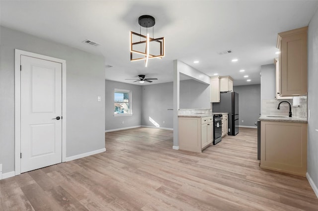 kitchen with visible vents, freestanding refrigerator, a sink, light wood-style floors, and backsplash