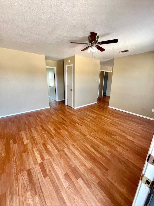 unfurnished room with ceiling fan, light hardwood / wood-style flooring, and a textured ceiling