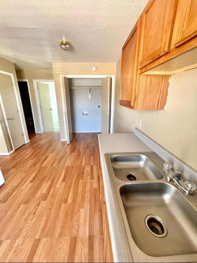 kitchen featuring sink, a textured ceiling, and light hardwood / wood-style flooring