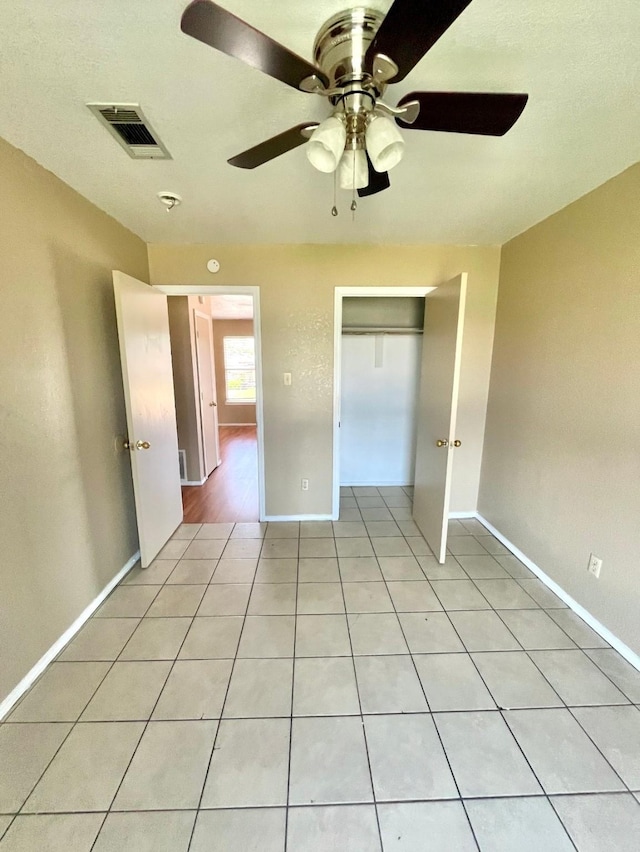 unfurnished bedroom with a closet, ceiling fan, and light tile patterned flooring