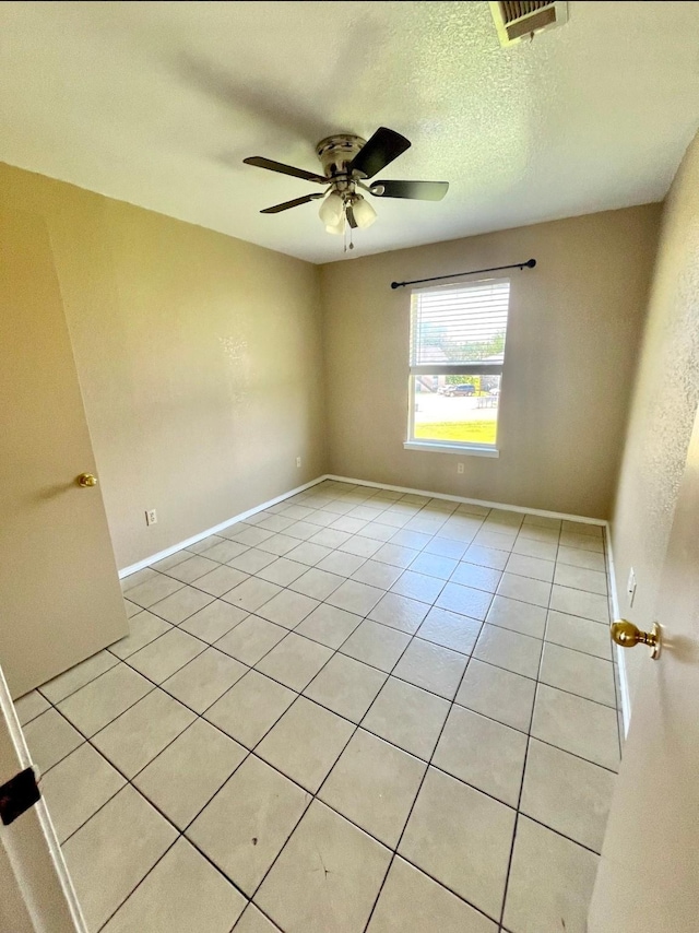 spare room featuring ceiling fan, light tile patterned floors, and a textured ceiling