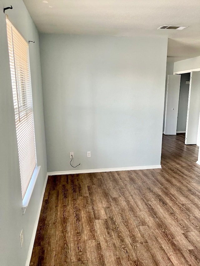 spare room featuring a healthy amount of sunlight and dark hardwood / wood-style flooring