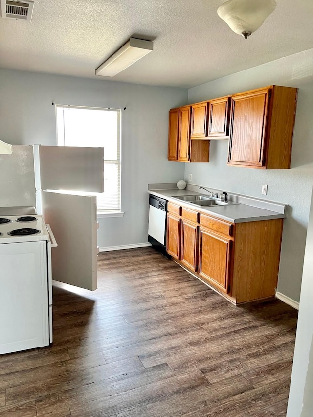 kitchen featuring a textured ceiling, dark hardwood / wood-style floors, white appliances, and sink