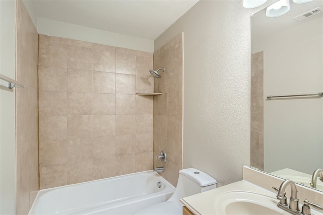 full bathroom featuring tiled shower / bath, vanity, and toilet